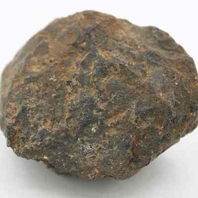 Closeup of basalt core or hammerstone: The image shows a rough, irregularly shaped rock with a dark, textured surface, featuring a mix of brown and gray hues, set against a white background.