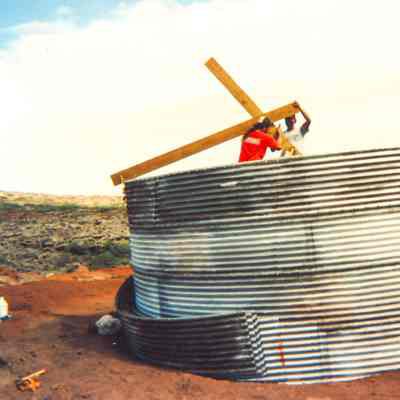 Two men placing wooden planks inside water catchment