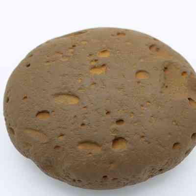 Closeup of worked cobble stone: The image shows a textured cobblestone with worked surface markings and indentations against a plain background.