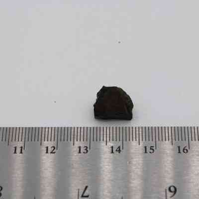 Small basaltic glass flake and ruler: The image depicts a small flake of basaltic glass next to a ruler, illustrating its size against the measuring tool.
