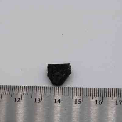 Small basaltic glass flake with ruler: A small basaltic glass flake is placed next to a ruler, displaying its size against the measurement scale.