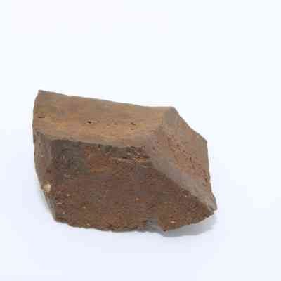 Closeup of profile of a glass core: The image shows a roughly hewn, angular piece of brown stone material, resembling a stone, with coarse texture, possibly containing or resembling a glass core.