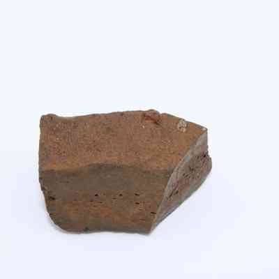 Closeup of glass core: The image shows a rough-textured, brownish glass core piece resting on a plain white surface, highlighting its uneven surface and jagged edges.