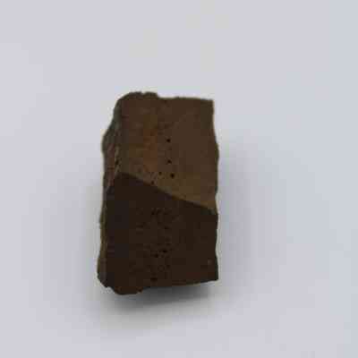 Closeup of glass core: The image showcases a weathered piece with a rough, angular surface resembling a glass core, set against a plain white background.