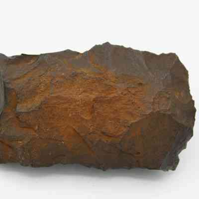 Closeup of adze fragment: The image shows a fragment of an adze with a rough, textured surface, showcasing its ancient craftsmanship.