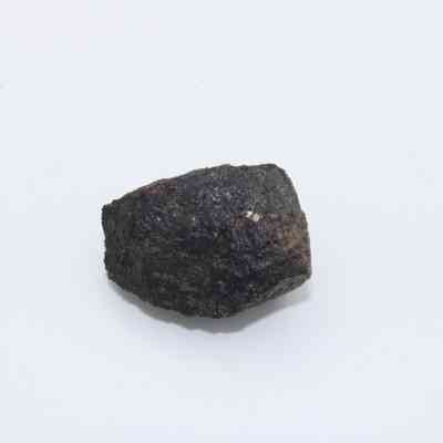 Basaltic glass core: A rough, dark, and uneven basaltic glass core piece is displayed against a plain white background, highlighting its textured surface.