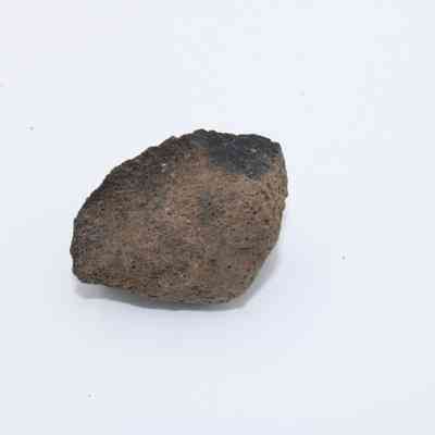 Profile of basaltic glass core: A piece of basaltic glass core is displayed, showcasing its rough texture and dark, earthy appearance against a white background.