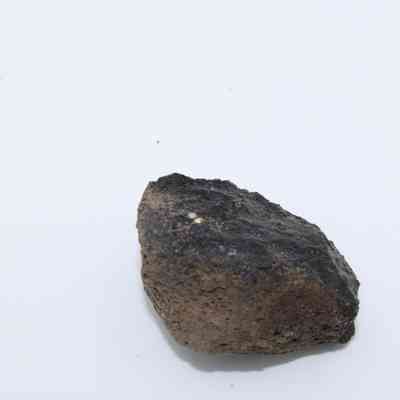 Closeup profile of basaltic glass core: The image shows a piece of basaltic glass core, displaying a rough, dark texture on a clean, white background.