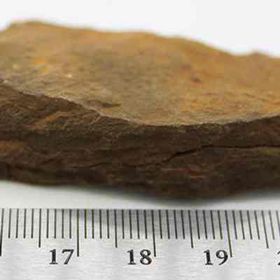 Whetstone (hoana) fragments placed together and with ruler: The image shows a rough, brown whetstone (hoana) fragment placed next to a ruler, indicating its size and texture.