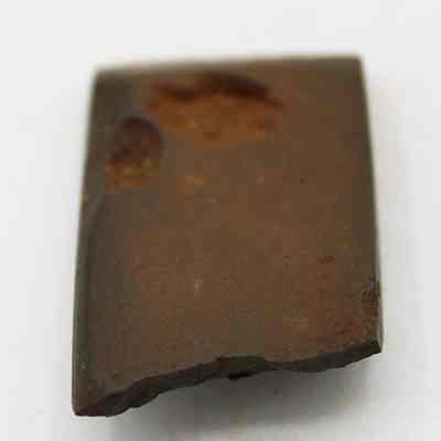 Basalt adze fragment: The image shows a weathered, brown, stone adze fragment with visible wear, suggesting historical use, resting on a plain, light background.