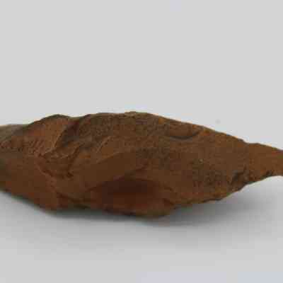 Top of a possible auger: The image shows a rust-colored, irregularly shaped object resembling a stone tool, possibly used as an auger.