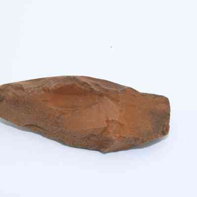 Closeup of a possible auger: The image shows a rough, brown stone tool that could resemble a primitive auger, possibly used for drilling.