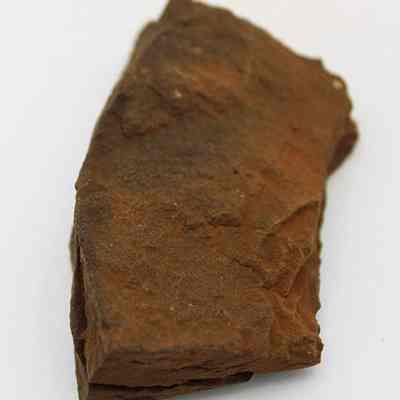Lengthwise view of whetstone (hoana) fragments placed together: The image shows irregular-shaped, brownish whetstone (hoana) fragments with a rough texture, resting against each other on a smooth, light-colored surface.