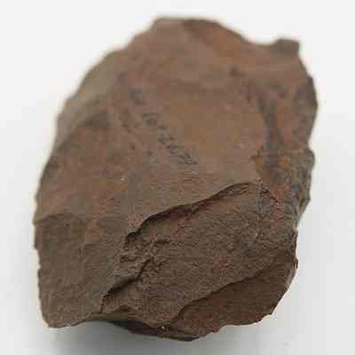 Close up of basalt adze blank: The image shows a close-up of an adze blank with rough, uneven surfaces and a brownish hue.