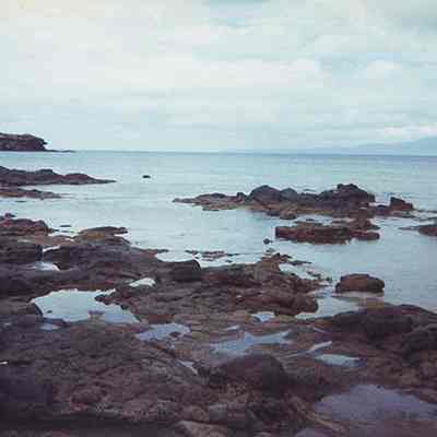 Two people standing on rocky coast at Kaulana