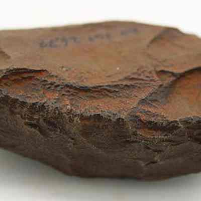 Close up profile of basalt adze blank: The image shows a rough, hand-sized piece of basalt with visible chipping marks on its surface, suggesting it may have been an ancient cutting or scraping implement.