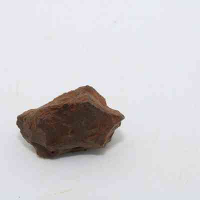 Profile of basaltic glass core: The image shows a rough, reddish-brown basaltic glass core with an irregular surface against a plain, white background.