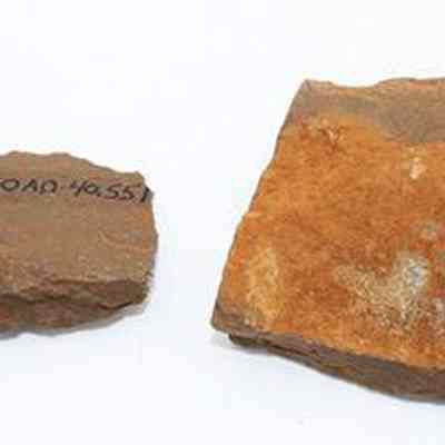 Two whetstone (honana) fragments with alternate id number visible: The image shows two brownish stone fragments, likely whetstone (hoana) pieces, with one marked with numbers.