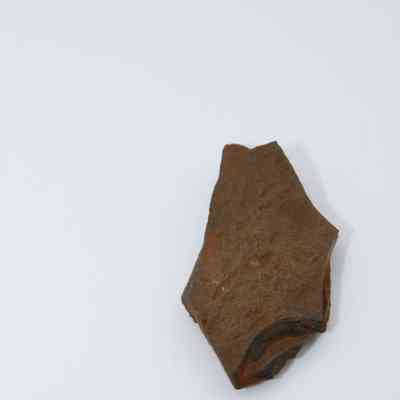 Lengthwise view of basaltic glass flake with metal ruler: The image shows a small fragment of basaltic glass on a white surface, with a ruler indicating approximate size.