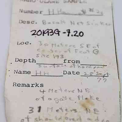 Artifact slip for basalt net sinker: The image shows a handwritten archaeological sample note detailing a basalt net sinker found at 30 meters southeast of Feature G.