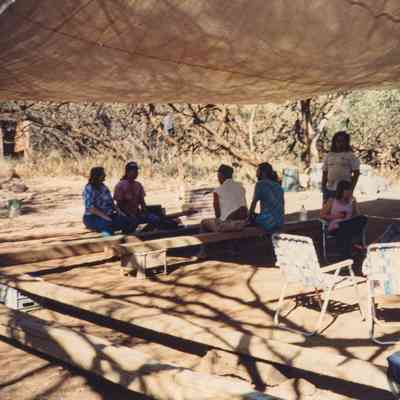 People sitting under tarp canopy