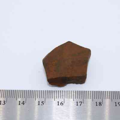 Basaltic glass core with ruler: The image shows a piece of brown basaltic glass core beside a ruler for scale, displaying its rugged shape and texture.