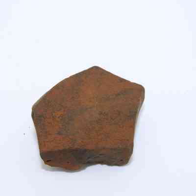 Closeup of basaltic glass core: The image displays a basaltic glass core, featuring a rough, irregular shape and earthy brown surface, against a plain white background.