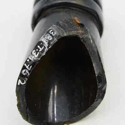 Glass bottle fragment with ruler: The image shows a dark, curved bottle fragment with visible markings near the broken edge, placed above a ruler for scale measurement.