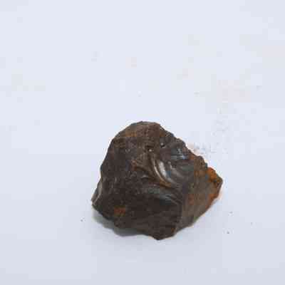 Closeup of basaltic glass core: The image shows a small, irregularly-shaped basaltic glass core resting on a plain white surface.