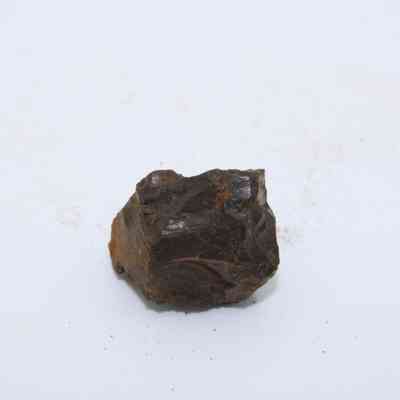 Closeup of basaltic glass core: The image shows a piece of basaltic glass core displaying rough, angular surfaces and deep brownish-black coloration on a plain background.
