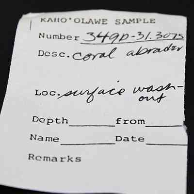 Artifact slip for a coral abrader: The image shows a paper labeled "KAHO‘OLAWE SAMPLE" with number 349D-31.3075. It describes "Coral abrader."