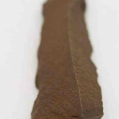 Lengthwise view of basalt awl: The image shows a close-up of a handcrafted stone awl, displaying its rough, pointed structure indicative of ancient tool-making techniques.