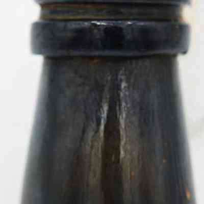 Glass bottle fragment (mouth and neck)): The image shows a dark-colored bottle fragment, featuring a narrow neck and a slightly flared base, likely broken from a larger, cylindrical vessel.