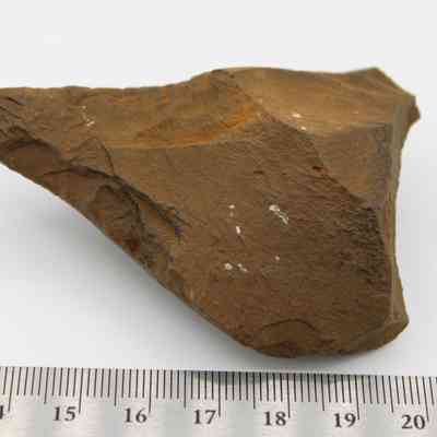 Basalt awl (kui houhou) and ruler: The image shows a brown, irregularly shaped stone with a pointed edge, placed on a white surface beside a ruler for size reference.