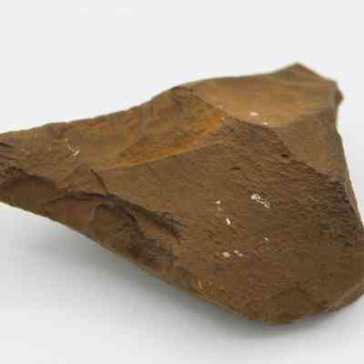 Closeup of basalt awl (kui houhou): The image shows a rough, triangular basalt awl, showcasing sharp edges and a textured, brown surface.