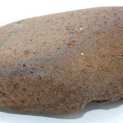 Closeup profile of a basalt hammerstone: The image shows a brown, textured stone with a smooth surface, used as a tool, resting on a white background.