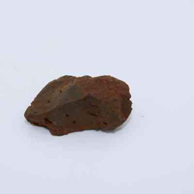 Closeup of basaltic glass core: The image shows a rugged, brown basaltic glass core with visible weathered texture and irregular surface features against a plain background.