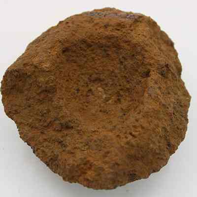 Closeup of broken cup or mortar: This image shows a roughly hewn, ancient-looking stone with a shallow, concave center, suggesting it's a primitive mortar used for grinding.
