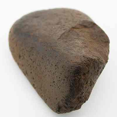 Closeup lengthwise view of a basalt hammerstone: The image shows a smooth, dark brown meteorite stone with a rough texture on its surface.