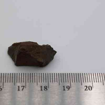 Glass core with ruler: The image shows a small, rough glass core next to a ruler, measuring approximately 2 centimeters and set against a plain background.