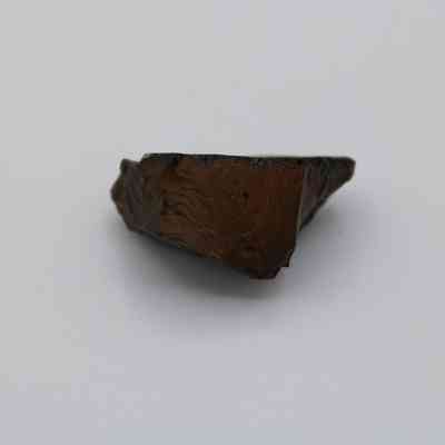 Glass core: The image shows a roughly textured, opaque glass core fragment placed against a neutral background.