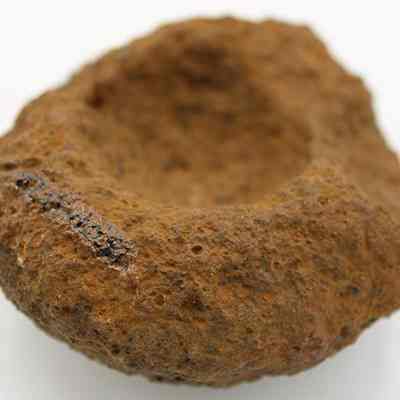 Base of broken cup or mortar with alternate id number visible: The image shows a rough, stone-like object with a deep, rounded indentation, resembling an ancient mortar used for grinding substances.