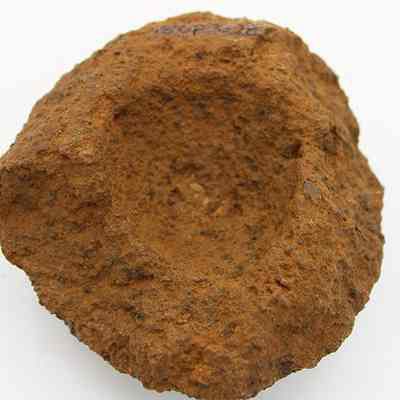 Closeup of broken cup or mortar: The image shows a rough, weathered stone object, likely a mortar, with a hollowed center, suggesting it was used for grinding.