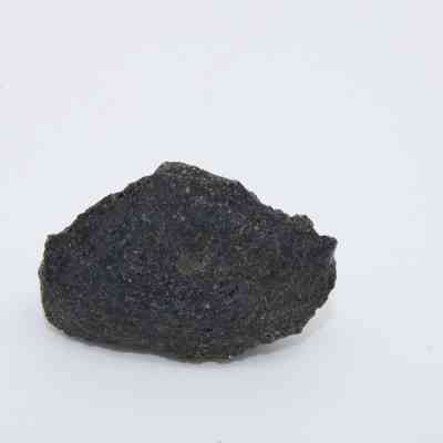 Closeup of one side a basaltic glass flake: A jagged piece of basaltic glass flake rests against a plain white background, showcasing its rough and textured surface.