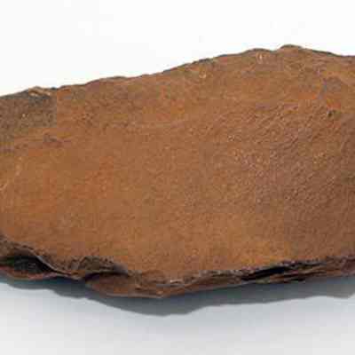 Basalt awl (kui houhou, kui iwi): The image depicts a roughly triangular, weathered stone tool, which resembles an ancient awl, with a brown, textured surface suitable for hand-held use