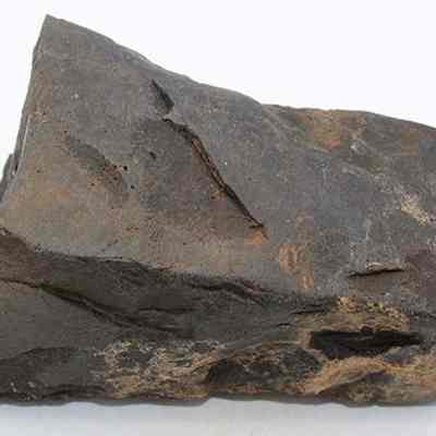 Basalt adze fragment: The image shows a fragment of a stone adze with a rough, weathered surface and jagged edges, suggesting its ancient origin and usage.