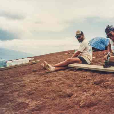 Two people working on wood plank on hardpan