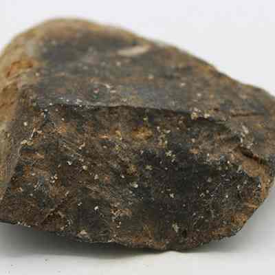 Side profile of basalt scraper: The image shows a rough, dark brown stone with uneven surfaces and a slightly angular shape, resting on a plain white background.