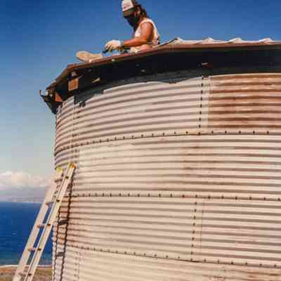 Man sitting on top of water tank