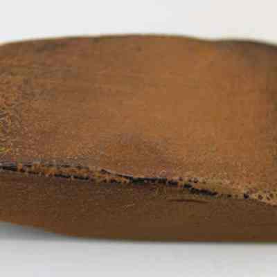 Basalt adze (ko'i): The image shows an ancient stone adze (ko'i) head with a rectangular shape and a smooth, polished brown surface, likely used for shaping materials.
